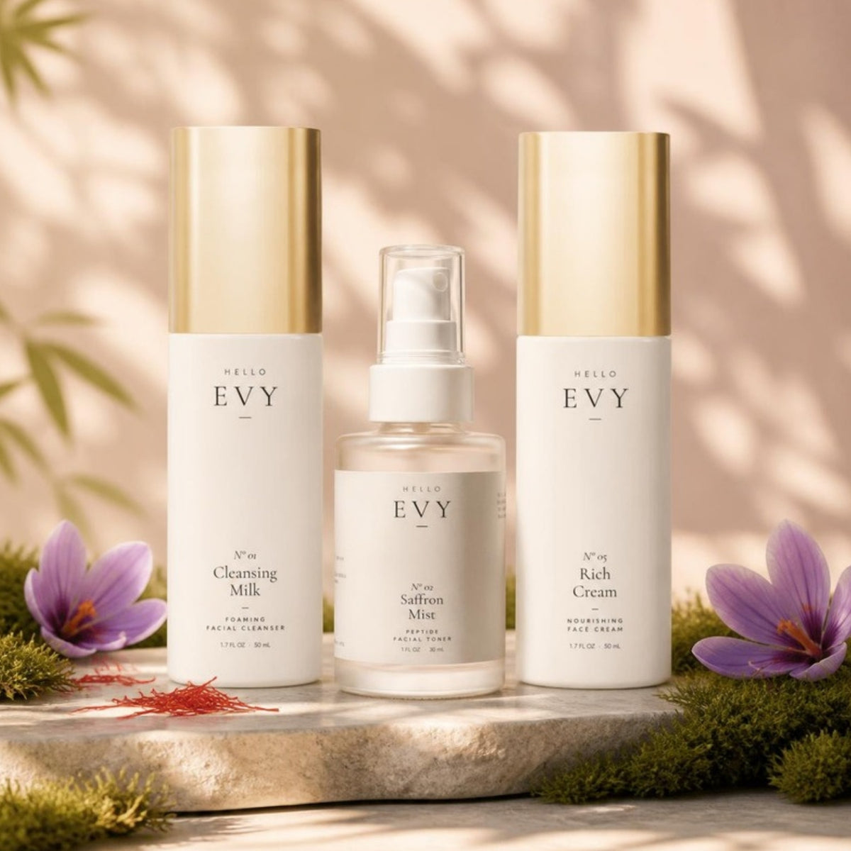 The Essentials Ritual: N° 01 Cleansing Milk, N° 02 Saffron Mist and N° 05 Rich Cream on a stone slab with moss and saffron crocus in warm sunlight