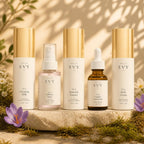 The Complete Ritual: all five Hello Evy formulas, N° 01 to N° 05, on a stone plinth with moss, saffron crocus and wildflowers